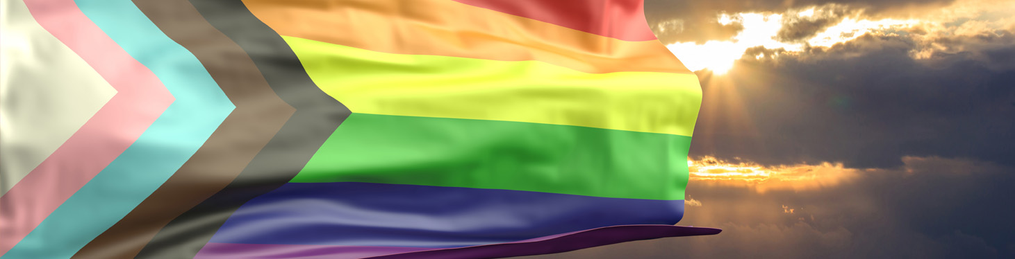 Progress LGBTQIA+ pride flag waves in front of a sunrise sky